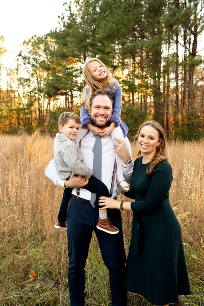 Family of four standing in tall grass smiling at the camera