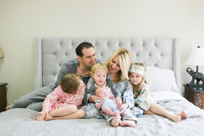 family of 6 on bed in pajamas with newborn