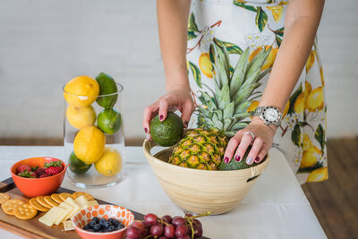 woman wearing a pineapple dress arranging fruit in a bowl