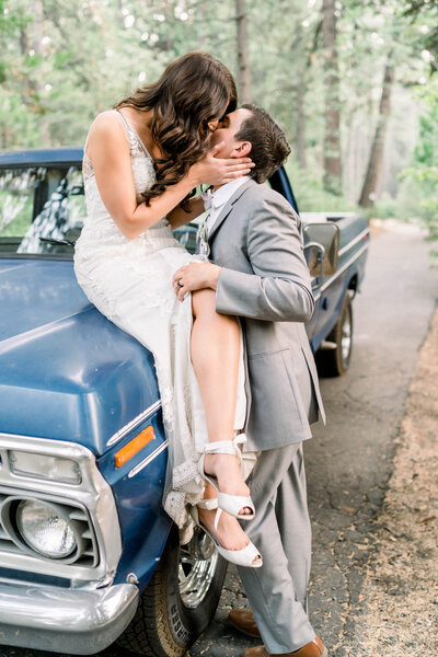 Bride and groom kiss on vintage blue truck at Park Winters in Winters, CA