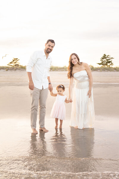 gorgeous family of three photographed during the golden hour on a Connecticut beach; the family are dressed in neutrals and the lighting helps create an ethereal portrait