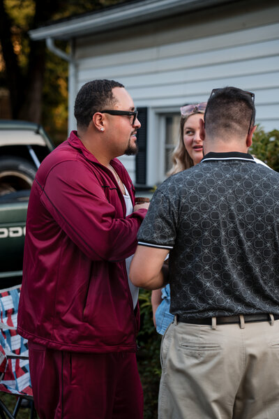 Two men in casual conversation outdoors during relaxed gathering – photographed by wedding photographer Niko Coric – Lumen Clarity Medi