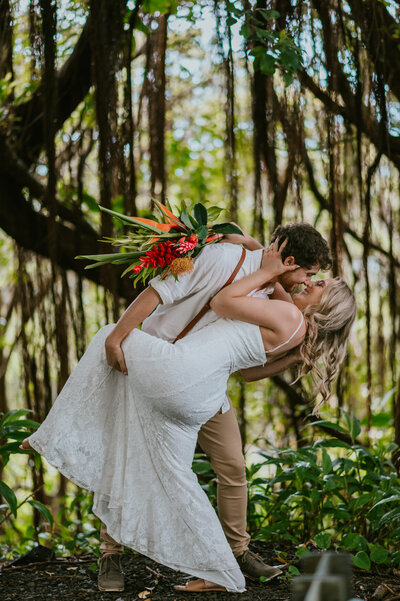 bride and groom dip kiss in jungle