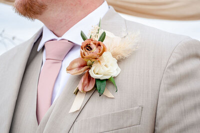 A boutonniere with pale rose and white flowers on the groom.