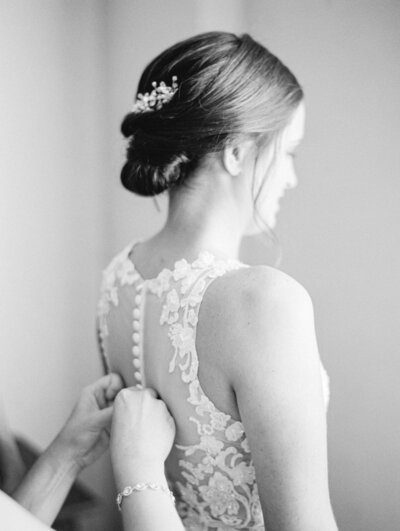 black and white image of bride getting her dress on