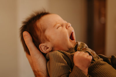 newborn yawning in dad's hands
