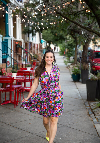 Ingrid Berrios, a branding photographer in Baltimore, prompts a woman to smile and swing her dress while walking down the streets of Hampden in Baltimore, Maryland on a summer evening.