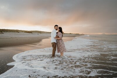 A couple being photographed at sunset with the mount in the background in Papamoa, photographed by Tashina Narelle, a Waikato, Auckland and Tauranga Photographer