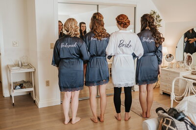 bride and bridesmaids standing in front of mirror in bridal suite