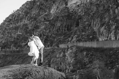 black and white image during engagement on Donner Summit. Couple dipping and kissing, white dress.