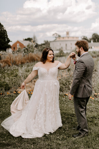 groom twirls bride around in wildflower field