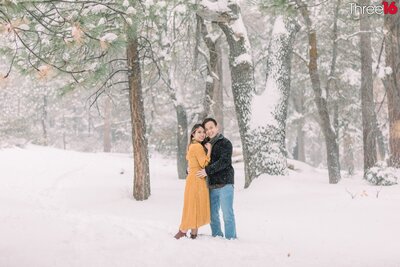 Engaged couple embrace each other in the cold off Big Bear Lake during engagement session