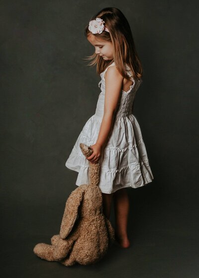fine art portrait of a little girl holding a teddy bear by the ear. Captured by kids photographer Tracy Miller Photography in Greensburg