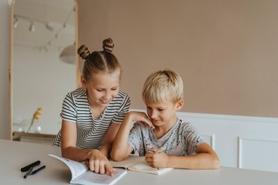 girl with pigtail buns and blond boy reading books together
