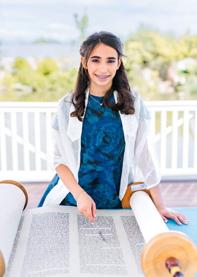 A teen girl reads from the torah at an outdoor temple