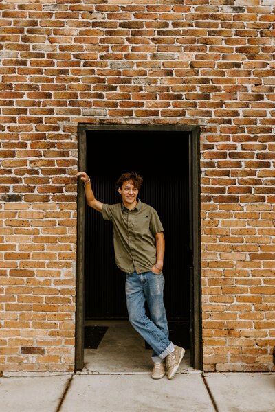 Ollie poses in front of a brick building in Bozeman for his senior photos.