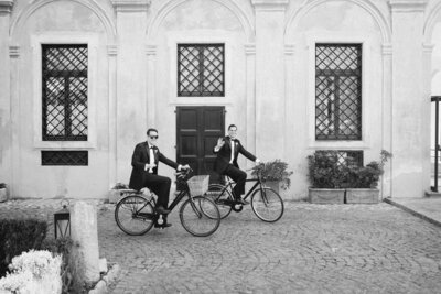 Two groomsmen on bikes on wedding day in Italy
