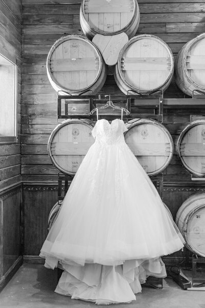 Wedding dress hanging on wine barrels in a wedding venue.