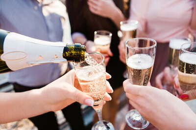 Close up of four people standing with a glass of champagne in their hand