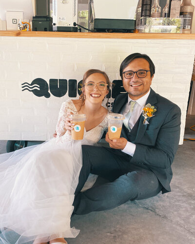 Bride and groom enjoying iced lattes from the Quigley Coffee Co mobile cart, showcasing wedding coffee catering service.