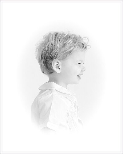 Black & white  heirloom vignette portrait of little boy's side profile.