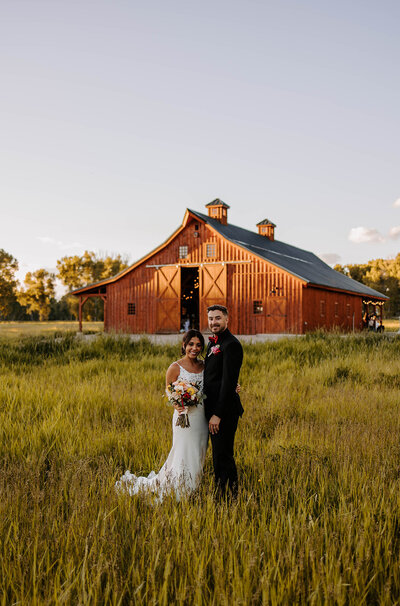 bride and groom in front of barn wedding venue