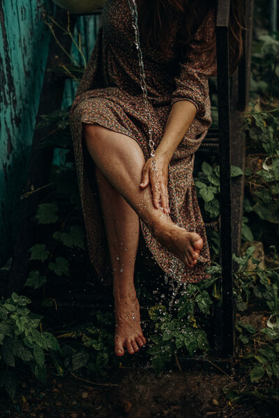 Woman in the forest pouring water on her feet