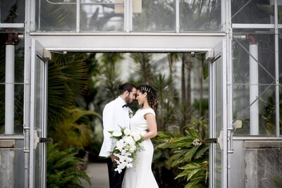 Model wedding couple standing at doors of greenhouse
