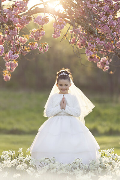 A young girl plays in a patch of white wildflowers at sunset in a park