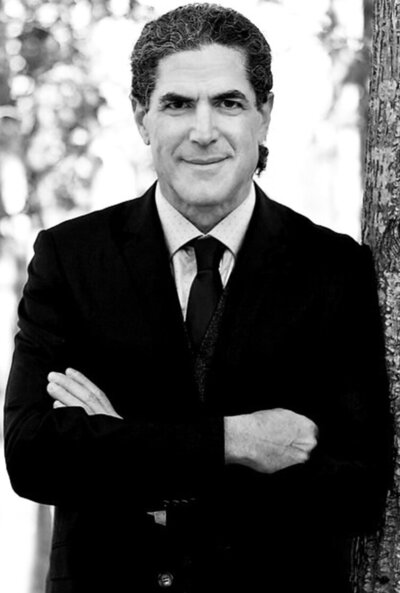 Business portrait featuring Andrew Riseman black and white dark suit arms folded across chest