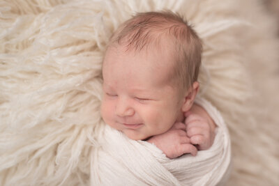 A close-up of a newborn baby boy, wrapped in white at his newborn session with Sharon Leger Photography.