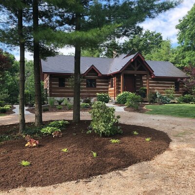 a log style home with custom landscaping design in the front yard