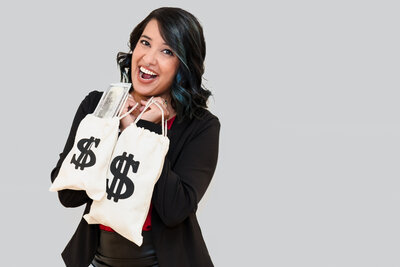 brand photo of a business coach posing with two bags with money sign