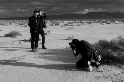 black and white Behind the scenes Mark Maryanovich photographing duo Polarcode standing in desert