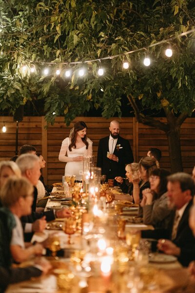 couple with guests at candle lit reception table