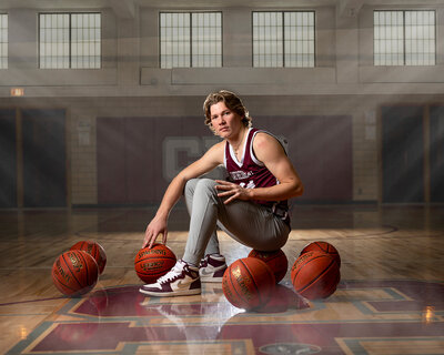 Senior guy poses with basketballs during his senior photo session with Jennifer Brandes Photography.