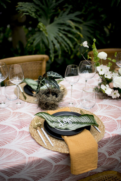 Closer look at table decor with plates, silverware, and large leaf