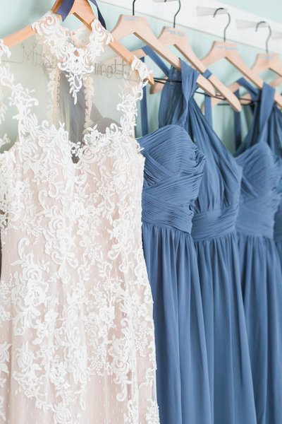 Wedding dress and bridesmaid dresses hanging on wooden hangers in a row