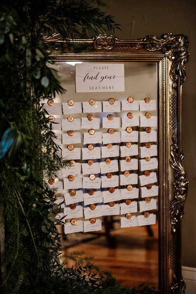 Seating chart with cards with seals on mirror, Unique Melody Events & Design helped with wedding (New England Wedding Planners)
