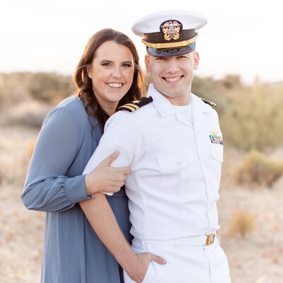 A man and woman in uniform pose for a photo in the desert.