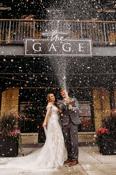 Bride and Groom in front of The Gage in Milwaukee spraying Champagne.