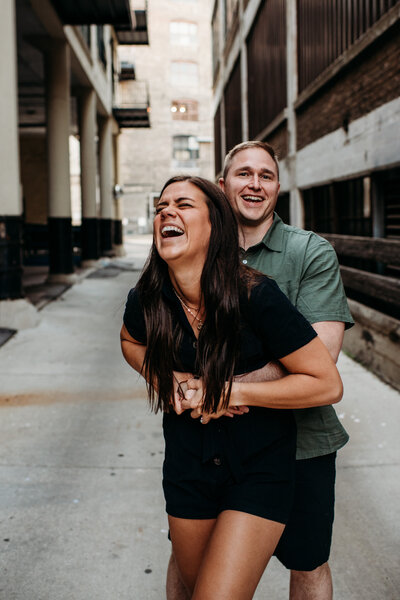 Man holding woman from behind as she laughs and giggles