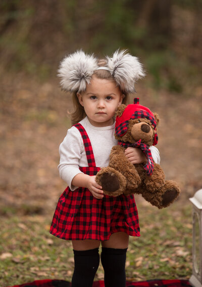 girl-with-red-buffalo-check-jumper-and-white-shirt-holding-teddy-in-matching-pattern-in-arlington-tx
