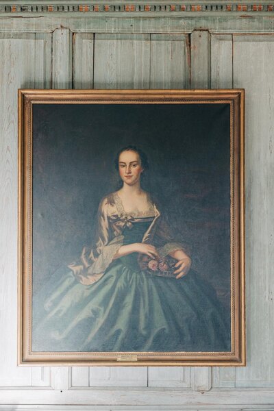 Portrait of a woman in a blue dress, captured by a luxury wedding photographer, displayed in an ornate frame on a wall.
