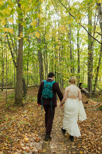 bride and groom kissing standing on a rocky shoreline with tall black rocks in the background and trees