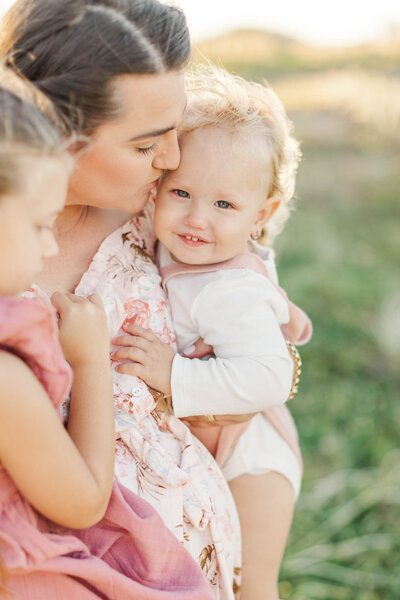 sweet portrait of a toddler during family portraits being cuddled by mum.