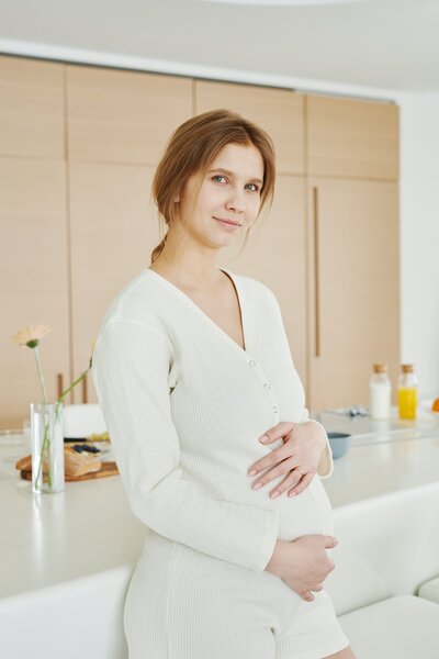 Pregnancy woman standing with hands on her belly.