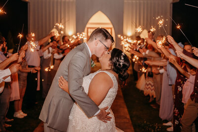 photo of bride and groom kissing in front of sparklers