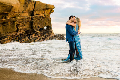 Couple kissing on the beach near a cliff in San Diego