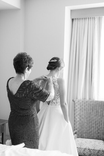 black and white image of bride getting her dress on
